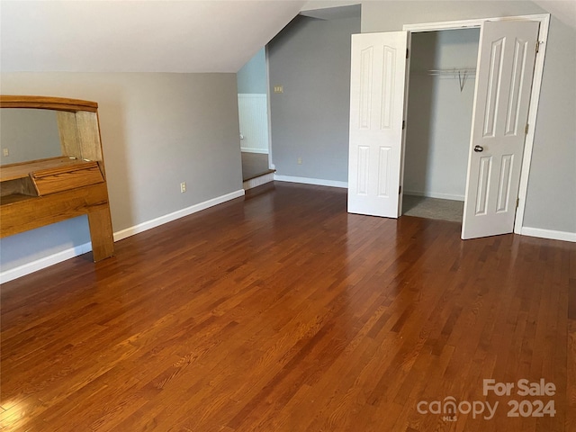 unfurnished bedroom featuring lofted ceiling, a closet, and dark hardwood / wood-style floors