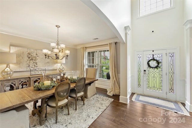 dining area featuring crown molding, a high ceiling, a chandelier, and dark hardwood / wood-style floors