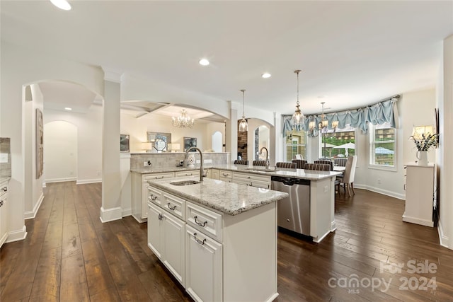 kitchen featuring hanging light fixtures, light stone countertops, a kitchen island with sink, dishwasher, and dark wood-type flooring