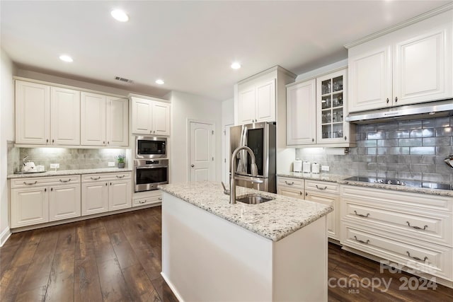 kitchen with a kitchen island with sink, stainless steel appliances, dark hardwood / wood-style floors, and white cabinetry