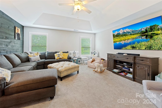 living room featuring ceiling fan, carpet flooring, and a tray ceiling