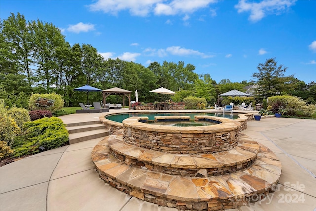 view of pool with an in ground hot tub and a patio