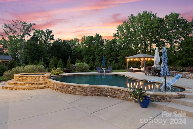 pool at dusk with a gazebo, a hot tub, and a patio