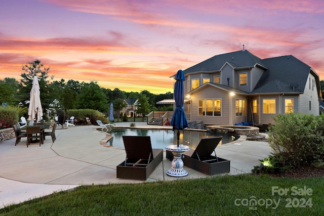 back house at dusk with a patio and a pool with hot tub