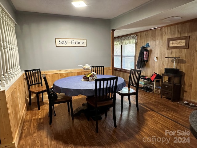 dining area featuring wood walls and dark hardwood / wood-style flooring