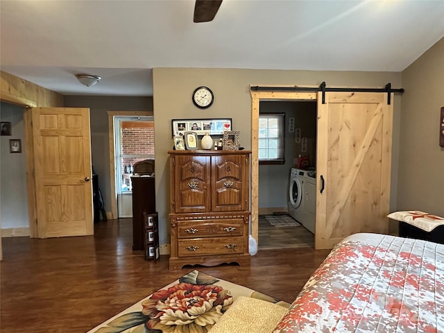 bedroom featuring ceiling fan, dark hardwood / wood-style floors, a barn door, and washing machine and clothes dryer