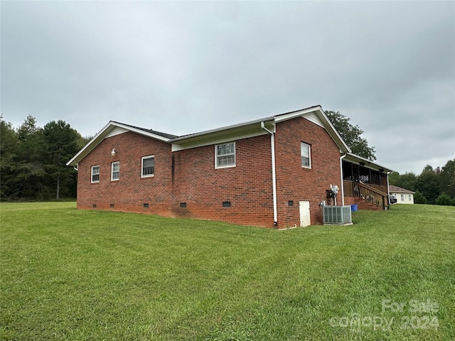 view of side of property featuring a lawn and central air condition unit