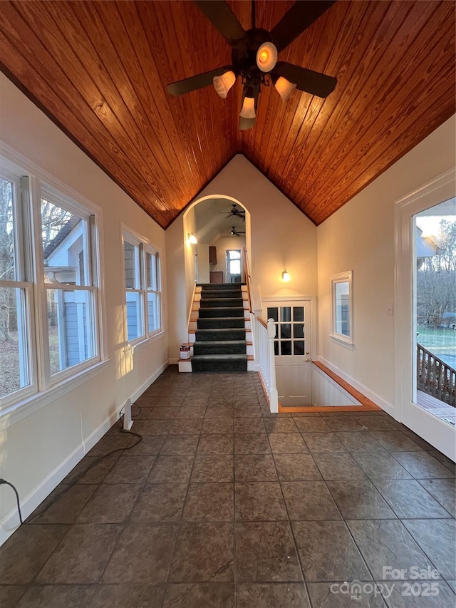 unfurnished living room with ceiling fan, lofted ceiling, a wealth of natural light, and wood ceiling