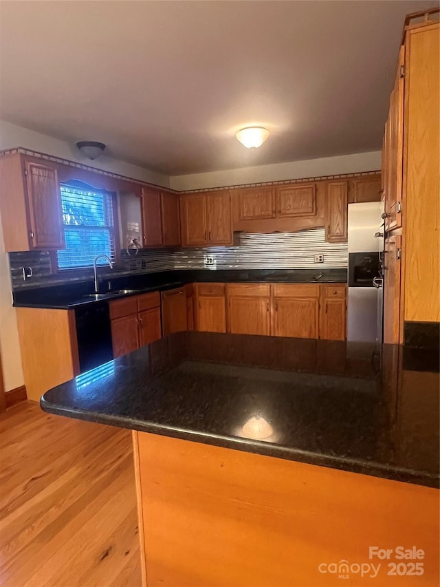 kitchen featuring sink, stainless steel fridge with ice dispenser, light hardwood / wood-style flooring, kitchen peninsula, and decorative backsplash