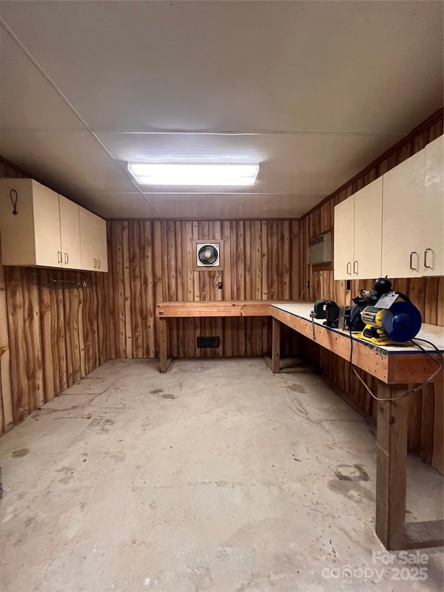 basement featuring wooden walls and a workshop area