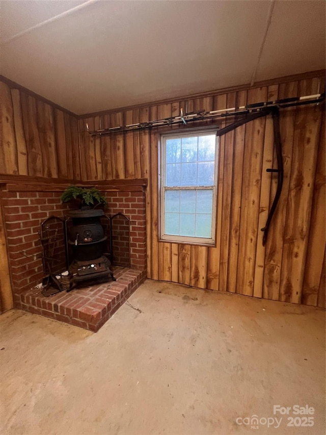 unfurnished living room featuring a wood stove and wooden walls