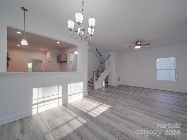 unfurnished living room featuring stairway, wood finished floors, ceiling fan with notable chandelier, baseboards, and recessed lighting