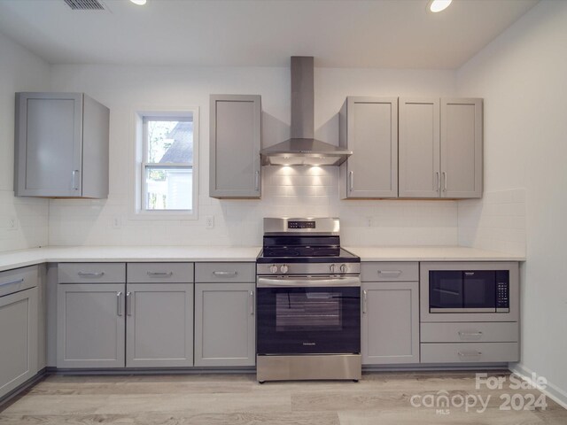kitchen featuring wall chimney range hood, gray cabinetry, built in microwave, and electric range