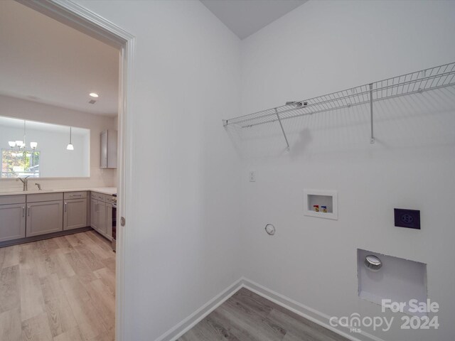 washroom featuring hookup for an electric dryer, light wood-style floors, hookup for a washing machine, gas dryer hookup, and laundry area