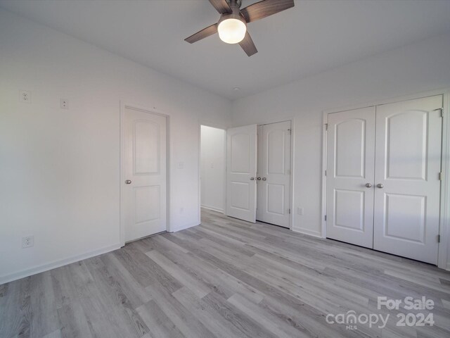 unfurnished bedroom with light wood-style floors, multiple closets, and baseboards