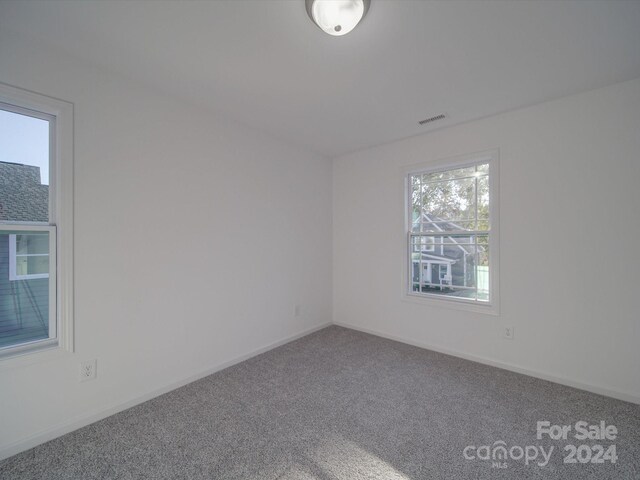 carpeted spare room with baseboards and visible vents