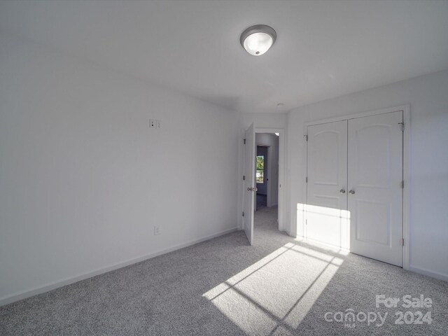 unfurnished bedroom featuring light carpet, a closet, and baseboards