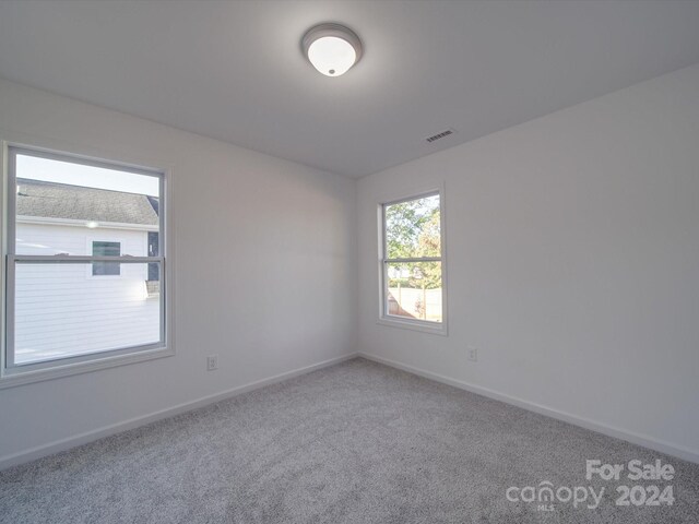 carpeted spare room featuring visible vents and baseboards