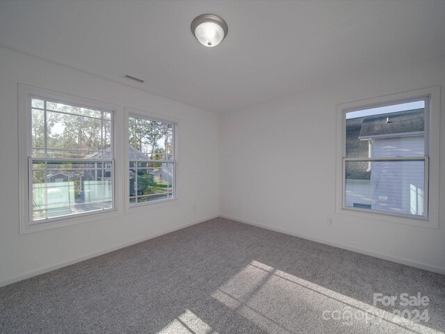 carpeted spare room featuring baseboards and visible vents