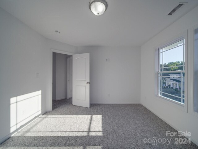 spare room with baseboards, visible vents, and carpet