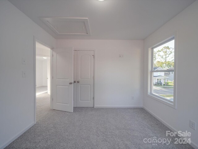 spare room featuring light carpet and baseboards
