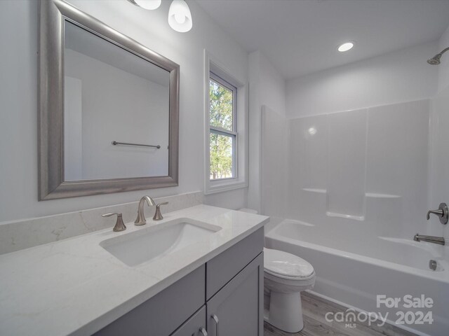 bathroom featuring wood finished floors, vanity,  shower combination, and toilet