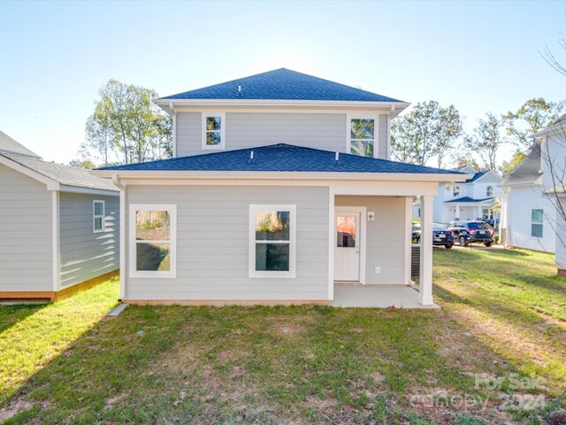 rear view of house with a yard and a shingled roof