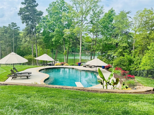 outdoor pool featuring a yard, a patio area, a water view, and fence