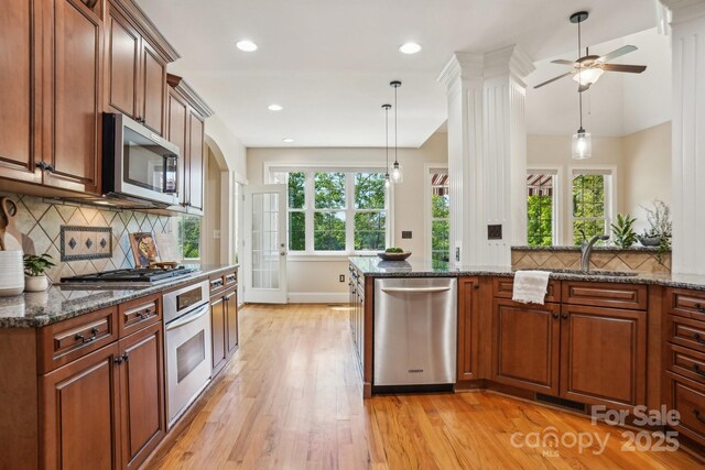 kitchen with brown cabinets, stainless steel appliances, light wood-type flooring, and a sink