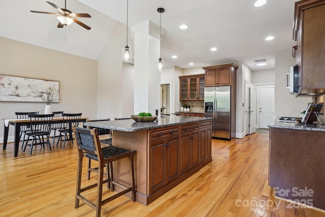kitchen featuring a kitchen breakfast bar, stainless steel appliances, light wood-type flooring, and glass insert cabinets