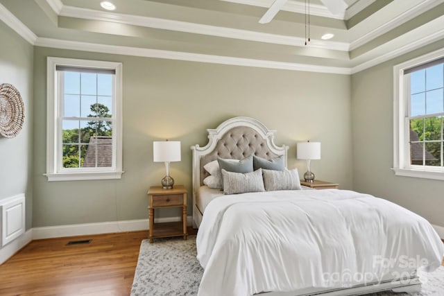 bedroom with crown molding, wood finished floors, a tray ceiling, baseboards, and recessed lighting