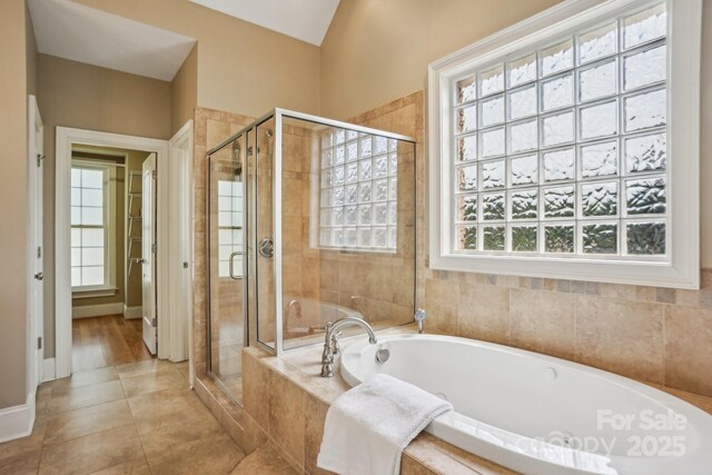 bathroom featuring a bath, tile patterned flooring, a shower stall, and baseboards