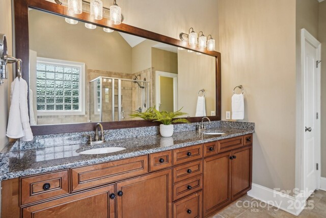 bathroom featuring a stall shower, double vanity, a sink, and tile patterned floors