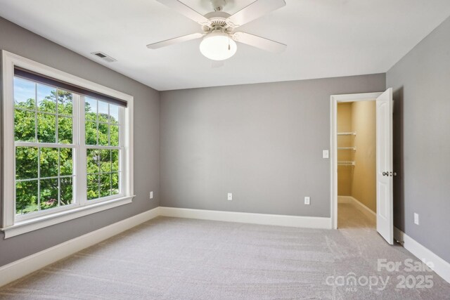 unfurnished room featuring baseboards, visible vents, a ceiling fan, and light colored carpet