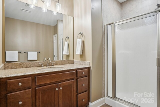 bathroom with visible vents, a shower stall, and vanity