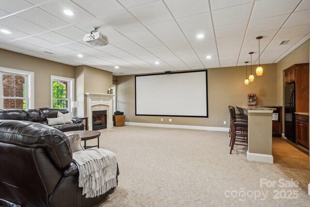 cinema room featuring recessed lighting, a fireplace with flush hearth, light colored carpet, and baseboards