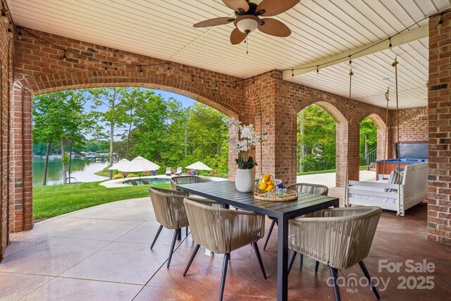 view of patio with outdoor dining space, a ceiling fan, a water view, and an outdoor pool