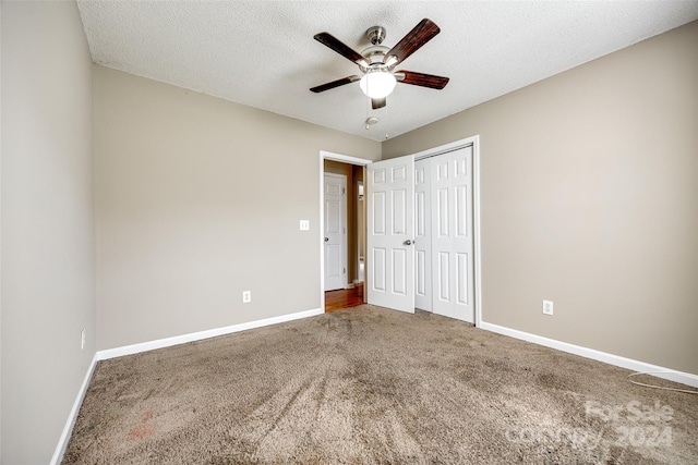 unfurnished bedroom featuring ceiling fan, carpet floors, a closet, and a textured ceiling