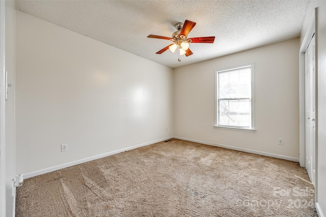 spare room with light carpet, a textured ceiling, and ceiling fan