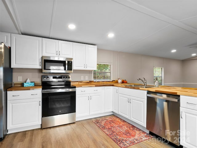 kitchen with a wealth of natural light, wooden counters, and appliances with stainless steel finishes