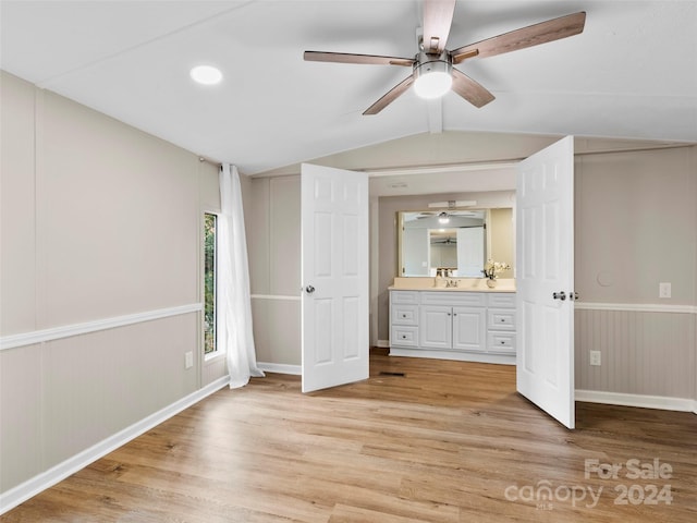 unfurnished bedroom featuring sink, vaulted ceiling, light hardwood / wood-style floors, ceiling fan, and ensuite bathroom