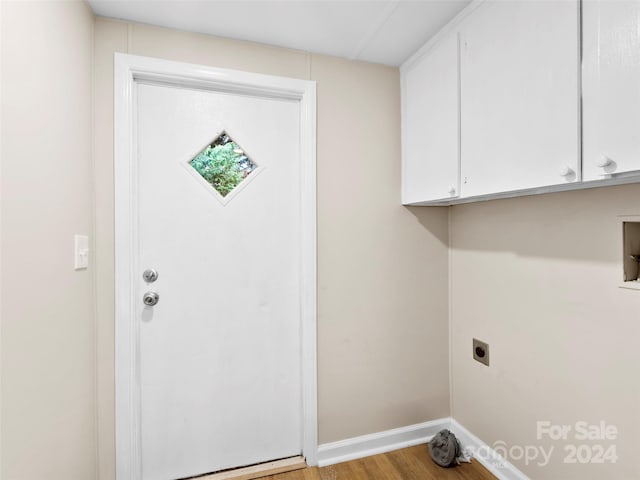 laundry room with hookup for an electric dryer, light hardwood / wood-style floors, and cabinets