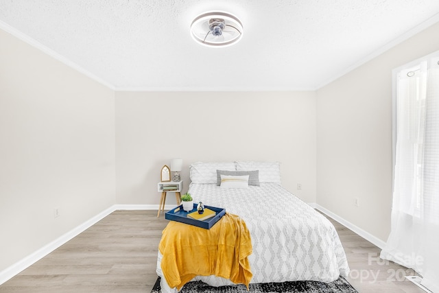 bedroom featuring crown molding, wood-type flooring, and a textured ceiling