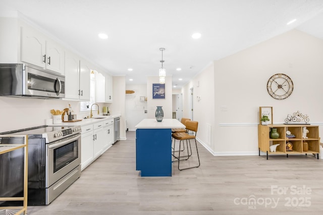 kitchen with a kitchen island, appliances with stainless steel finishes, sink, white cabinets, and a kitchen bar