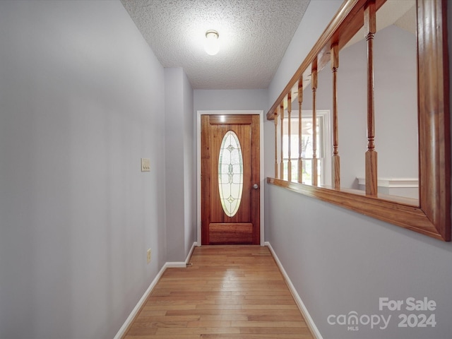 doorway with a textured ceiling and light hardwood / wood-style floors