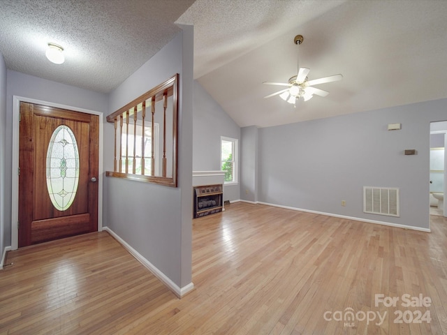 foyer entrance featuring lofted ceiling, light hardwood / wood-style floors, ceiling fan, and a textured ceiling