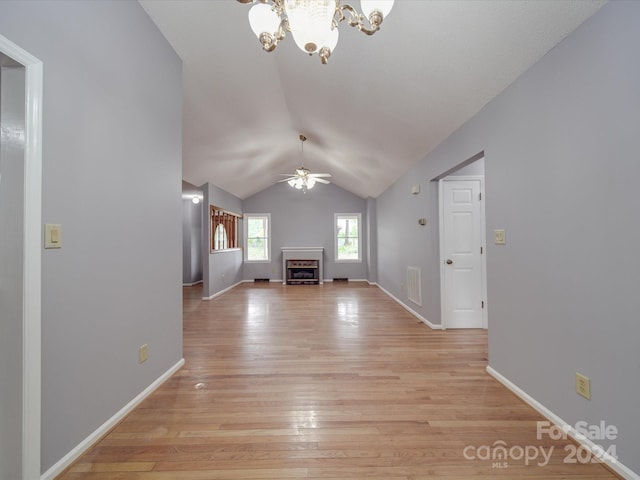 interior space with light wood-type flooring, ceiling fan with notable chandelier, and lofted ceiling