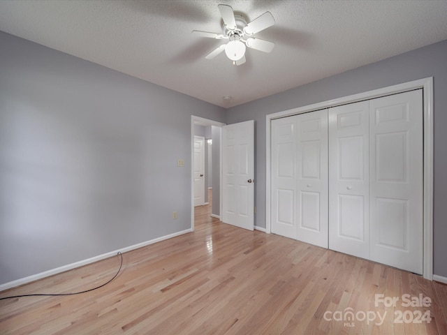 unfurnished bedroom with light wood-type flooring, a textured ceiling, ceiling fan, and a closet