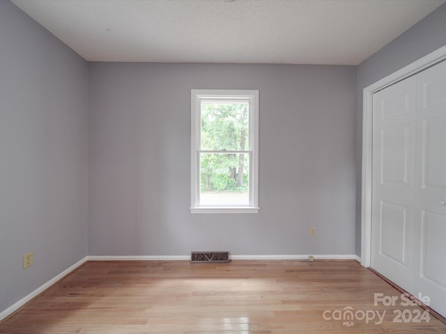 spare room with light hardwood / wood-style floors and a textured ceiling