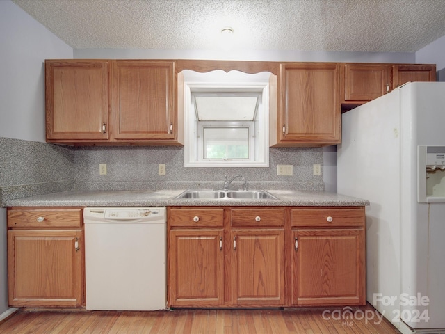 kitchen with a textured ceiling, light hardwood / wood-style floors, tasteful backsplash, sink, and white appliances